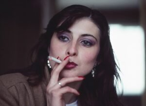 Young woman smoking a cigarette in her lovers hotel room