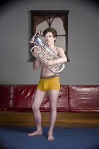 Young man playing a Tuba in his underwear