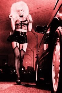 Prostitute working the streets at night approaches a car