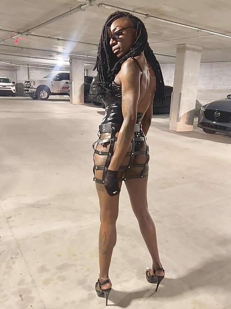 Black fetish beauty in underground parking garage wearing next to nothing