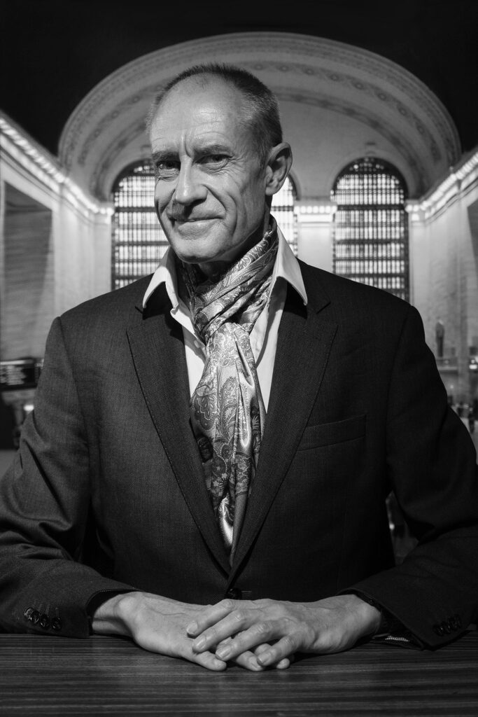 Portrait of a styish executive seated at a desk in Grand Central Station NYC wearing a KVaughn Scarf