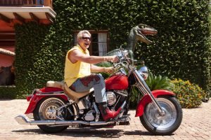 Thomas Kramer. guy on a motorcycle in front of animal sculpture at his home